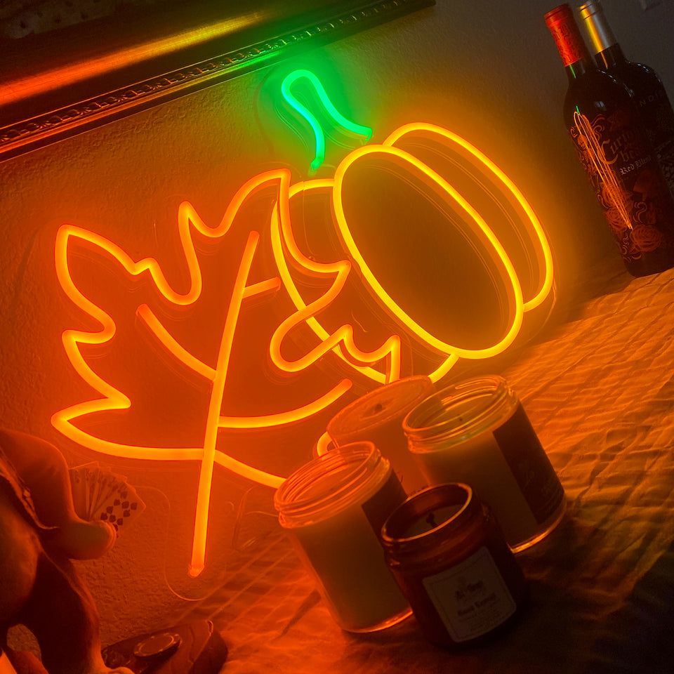 A neon sign with a leaf, pumpkin, and acorn on it. - Neon orange