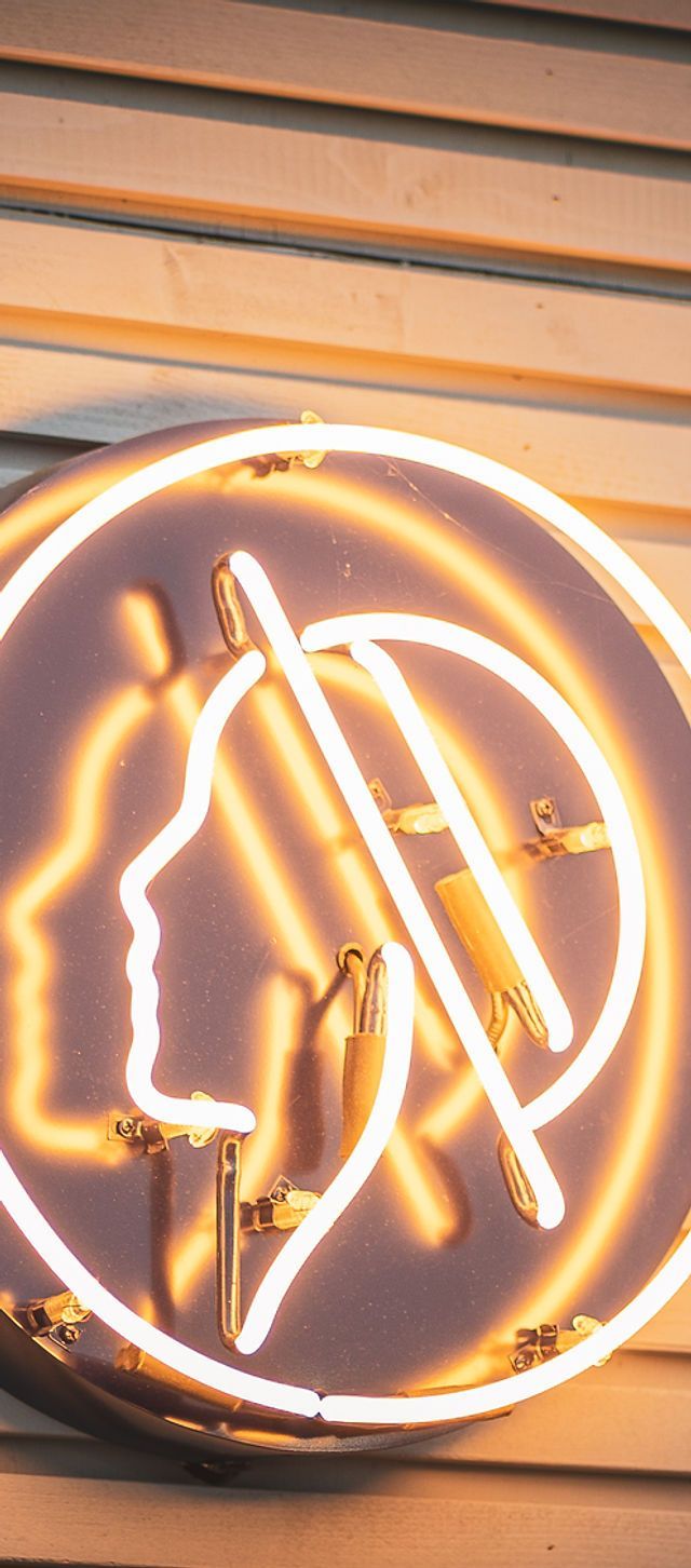 A neon sign with a profile of a woman's head - Neon orange
